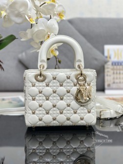 迪奥 Lady Dior 四格蝴蝶钉 内里配羊筋采用羊皮革精心制作饰以藤格纹缉面线和金色饰面蝴蝶铆钉提升格调时尚典雅的设计经久不衰。搭配带有浅金色饰面金属蝴蝶吊饰和白色树脂珠饰的 D.I.O.R. 吊饰为精美的轮廓增添一分灵动。搭配可拆卸的皮革细肩带，可手提或斜挎。尺寸：20 x 17 x 8 厘米，型号：M