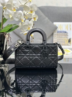 迪奥 Lady D-Sire 小号油蜡皮黑色，配三枚点钻徽章，本季新品系列发布秀精彩亮相，从 Lady Dior 手袋经典的优雅气质汲取灵感。采用黑色褶皱牛皮革精心制作，经过重新诠释突显休闲款式，打造都市造型。点缀以超大藤格纹缉面线，搭配同色调哑光金属 D.I.O.R. 吊饰，增添现代风范。小号款式，设计别致，肩带可饰以经典徽章彰显个性，可手提或斜挎。宽肩带包含三枚徽章，寸：26 x 15 x 8 厘米，型号M1150、 独家实物拍摄 配送全套包装白色礼盒