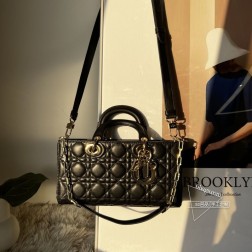 迪奥 全新 Lady D-Joy 手袋延续标志性 Cannage 藤格纹、D.I.0.R.字母吊饰、双手柄设计，包身演变为 East-West 扁长造型，相比方形包包显得更为随性利落。黑色款采用羊皮革制作而成，包包配有一条可拆卸链条肩带和一条可拆卸可调节的皮革肩带，可手提、肩背或斜挎，是日常造型的理想之选。尺寸：26x13.5x5cm